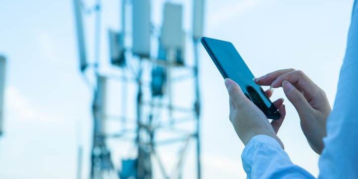 Human hand using mobile phone near 4G,5G communications tower Unlocking Reliable Event Coverage with Solaris Mobile Internet Towers