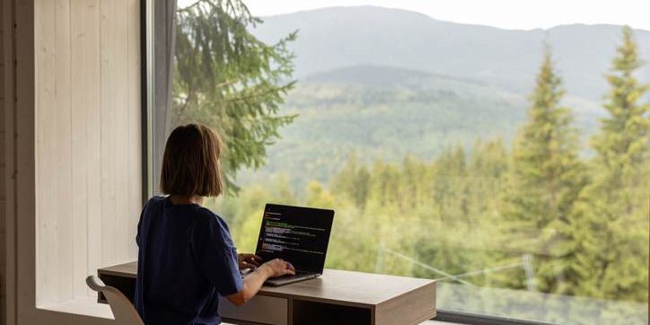 Woman works on laptop remotely in house on nature Improving Connectivity: How Wifi Towers are Bridging the Gap in Remote Areas